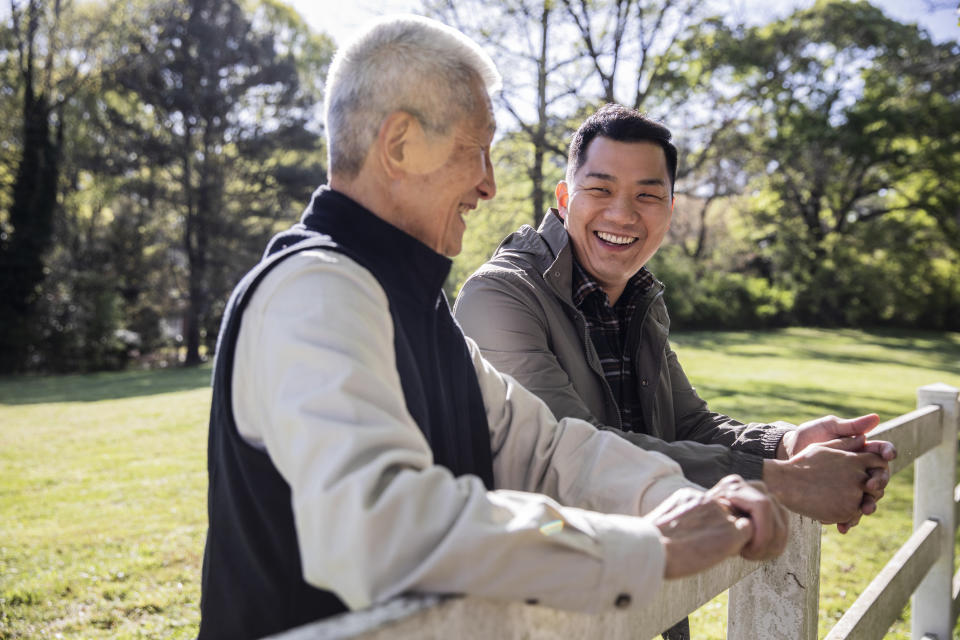 A father and his son laughing near a fence