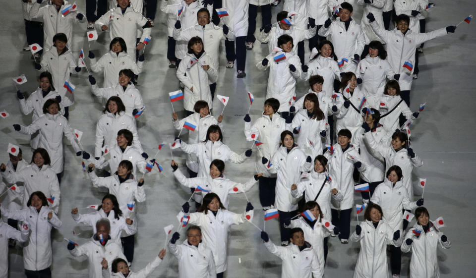 Ayumi Ogasawara of Japan holds her national flag and enters the arena with teammates during the opening ceremony of the 2014 Winter Olympics in Sochi, Russia, Friday, Feb. 7, 2014. (AP Photo/Charlie Riedel)