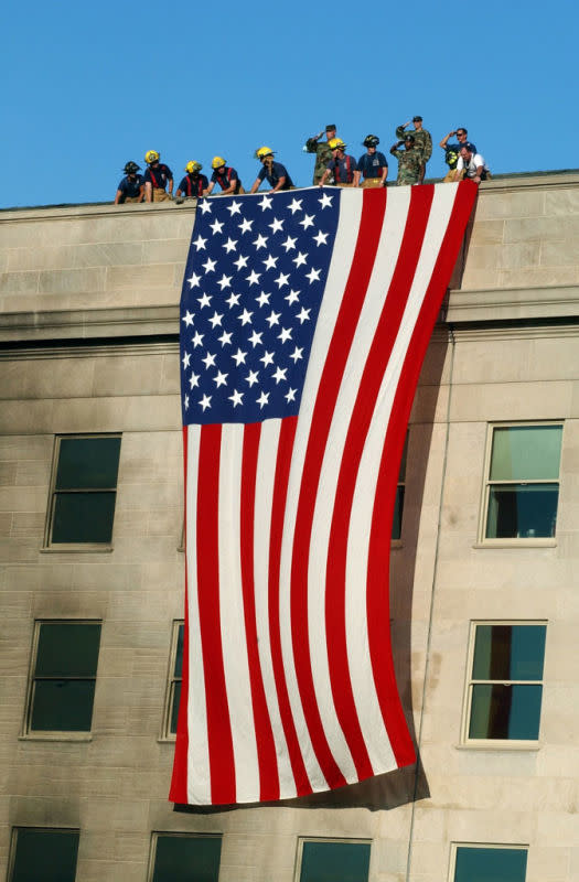 <p>Photo byMichael W. Pendergrass /U.S. Navy/Getty Images</p><p>Military service members salute as fire and rescue workers unfurl a huge American flag on September 13, 2001, over the side of the Pentagon in Arlington, VA.</p>