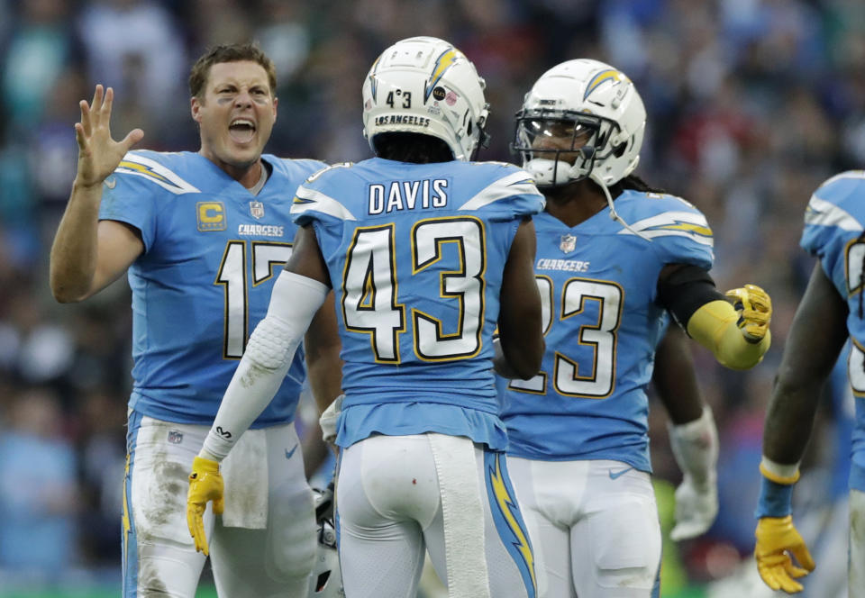 Los Angeles Chargers quarterback Philip Rivers (17), left, celebrates with teammates after a successful defensive play near the end of the second half of an NFL football game against Tennessee Titans at Wembley stadium in London, Sunday, Oct. 21, 2018. Los Angeles Chargers won the match 20-19. (AP Photo/Matt Dunham)