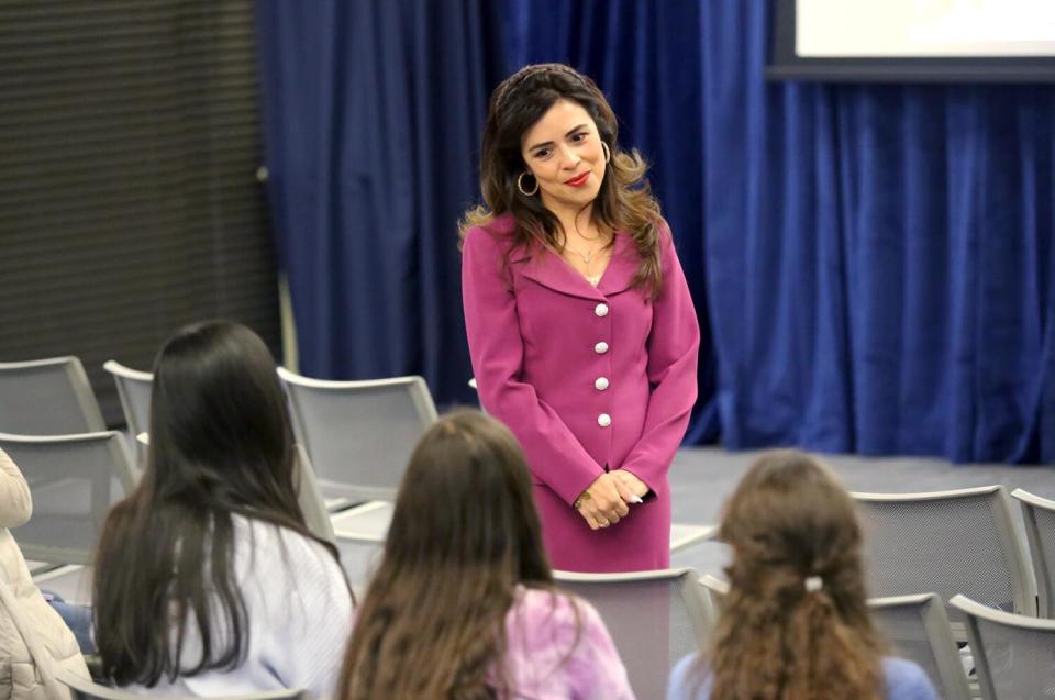 A woman stands near seated audience members in an auditorium.