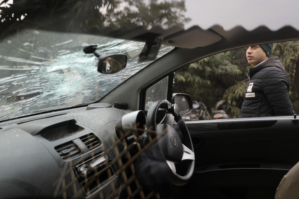 A student walks past a car vandalized in Sunday's assault by masked assailants at the Jawaharlal Nehru University in New Delhi, India, Monday, Jan. 6, 2020. More than 20 people were injured in the attack opposition lawmakers are trying to link to the government. (AP Photo/Altaf Qadri)