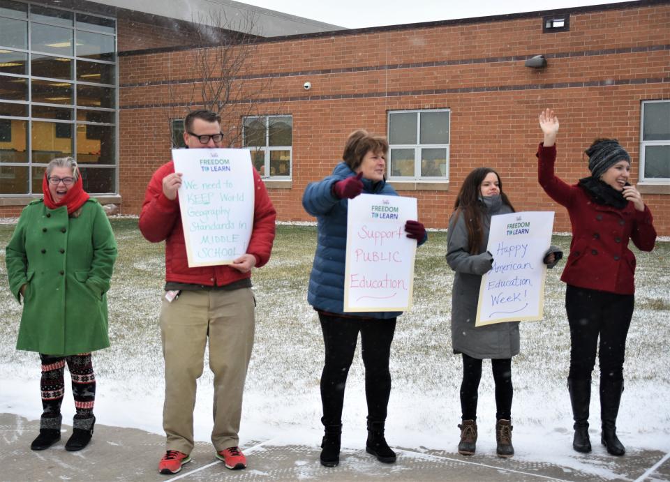 Matt Baumgartner, second from left, a current events teacher at North Middle School in Harrisburg, holds a sign reading "We need to keep world geography standards in middle school." Baumgartner stands with his fellow educators at the school on Wednesday morning, Nov. 16, 2022, as part of a "walk-in" to school to stand against the proposed social studies standards.