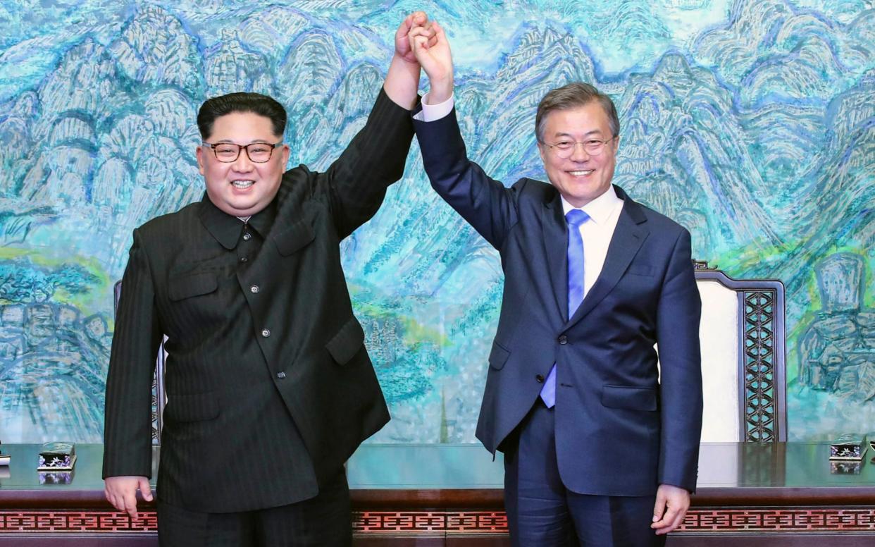 North Korean leader Kim Jong-un and South Korean President Moon Jae-in raise their hands after signing a joint statement at the border village of Panmunjom  - Korea Summit Press Pool