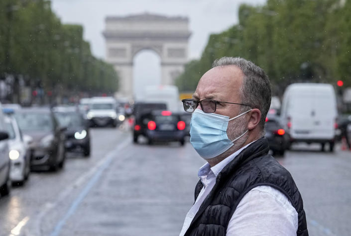 A man wearing a face masks to protect against coronavirus crosses the Champs Elysees avenue in Paris, Monday, July 12, 2021. France's President Emmanuel Macron is hosting a top-level virus security meeting Monday morning and then giving a televised speech Monday evening, the kind of solemn speech he's given at each turning point in France's virus epidemic. (AP Photo/Michel Euler)
