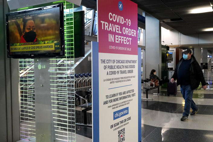 A traveler walks through Terminal 3 as a COVID-19 travel order sign is displayed at O'Hare International Airport in Chicago, Sunday, Nov. 29, 2020. Friday's total of new cases is the next-to-lowest daily number in the past 12 days, but Illinois state officials are bracing for another surge after many people around the country traveled for Thanksgiving and celebrated with family and friends. (AP Photo/Nam Y. Huh)
