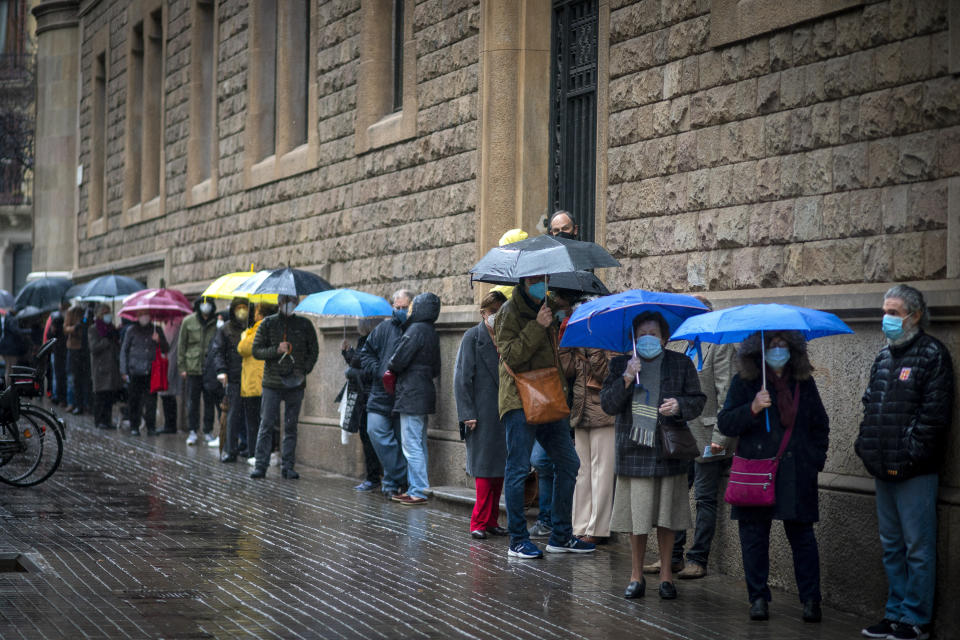 People line up outside a polling station, before casting their vote for the regional Catalan election in Barcelona, Spain, Sunday, Feb. 14, 2021. Over five million voters are called to the polls on Sunday in Spain's northeast Catalonia for an election that will measure the impact of the coronavirus pandemic on the restive region's secessionist movement. (AP Photo/Emilio Morenatti)