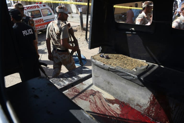 Pakistani security personnel gather around a police van after an attack by gunmen on officers guarding a polio vaccination team in Karachi on April 20, 2016