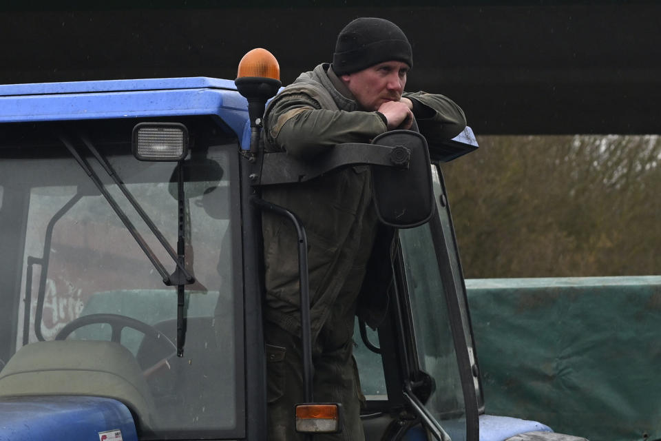 A French farmer stands on his tractor as farmers block a highway, Tuesday, Jan. 23, 2024 near Beauvais, northern France. Farmers have for months been protesting for better pay and against what they consider to be excessive regulation, mounting costs and other problems. (AP Photo/Matthieu Mirville)