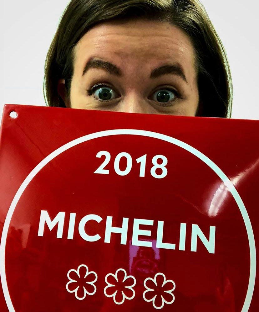 riley behind a sign promoting her restaurant's 3 michelin stars