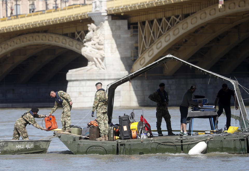 Rescue team members are seen on a barge floating on the Danube river where a sightseeing boat capsized in Budapest, Hungary, Saturday, June 1, 2019. As divers descended Friday into the Danube, Hungarian authorities predicted it would take an extended search to find the 21 people still missing after a boat carrying South Korean tourists was rammed by a cruise ship and sank into the river in Budapest. (AP Photo/Laszlo Balogh)