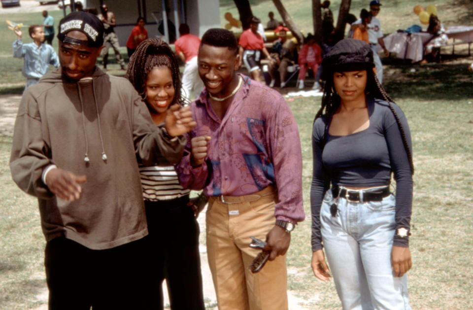 Black men and women are on a lawn looking at what is going on around them, with smiling and curious facial expressions