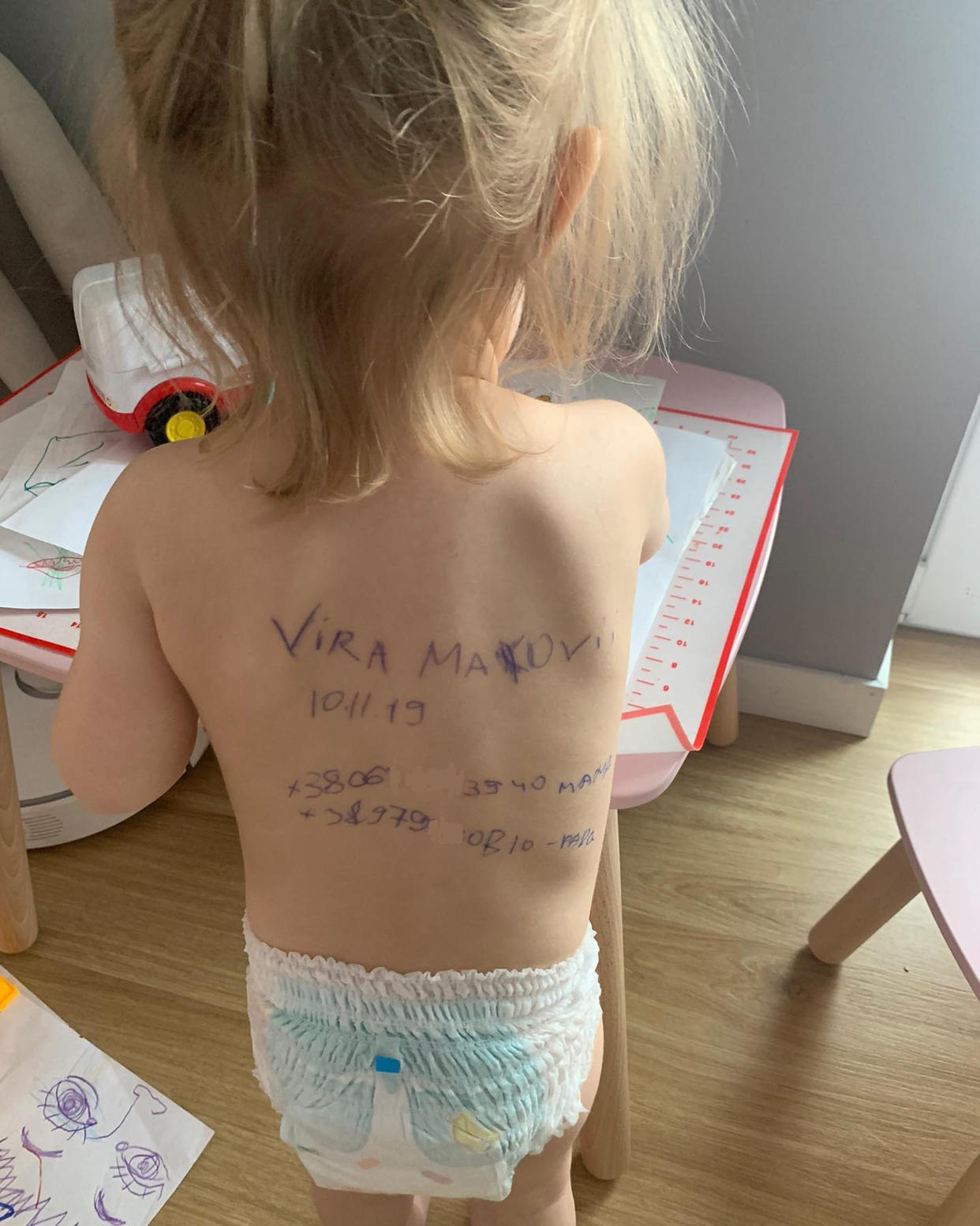 Sasha's daughter, pictured with her grandparent's contact information written on her back. (Courtesy Sasha)