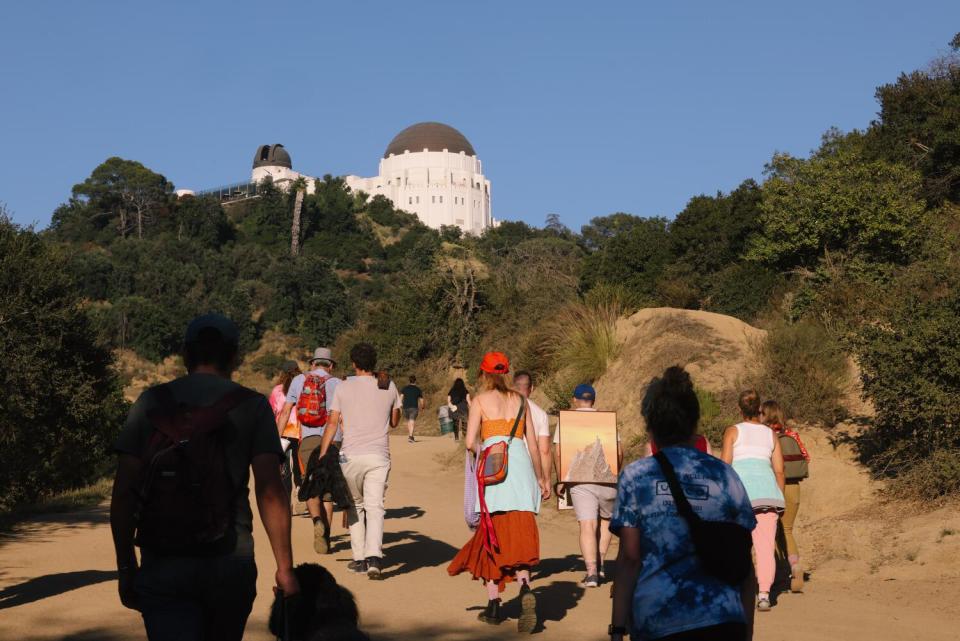 A group of art goers participate in a sunset art hike to the top of a trail.