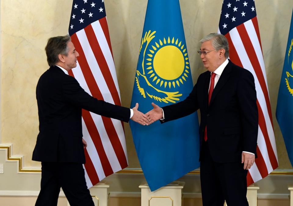 Antony Blinken shaking hands with Kassym-Jomart Tokayev in front of US and Kazakh flags.