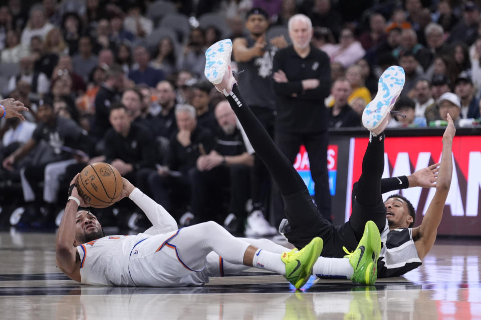 New York Knicks guard Jalen Brunson, left, look to pass the ball after he collided with San Antonio Spurs center Victor Wembanyama, right, during the second half of an NBA basketball game in San Antonio, Friday, March 29, 2024. (AP Photo/Eric Gay)