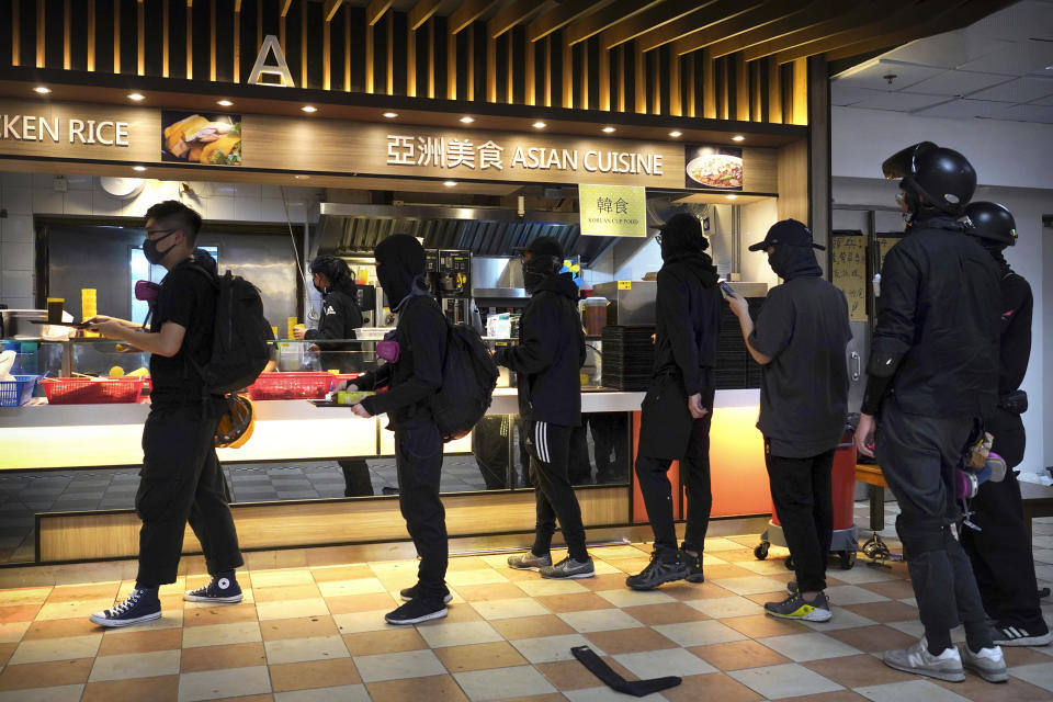 Protesters line up for food in a canteen at Hong Kong Polytechnic University in Hong Kong, Friday, Nov. 15, 2019. Protesters who have barricaded themselves in a Hong Kong university partially cleared a road they were blocking and demanded that the government commit to holding local elections on Nov. 24. (AP Photo/Vincent Yu)