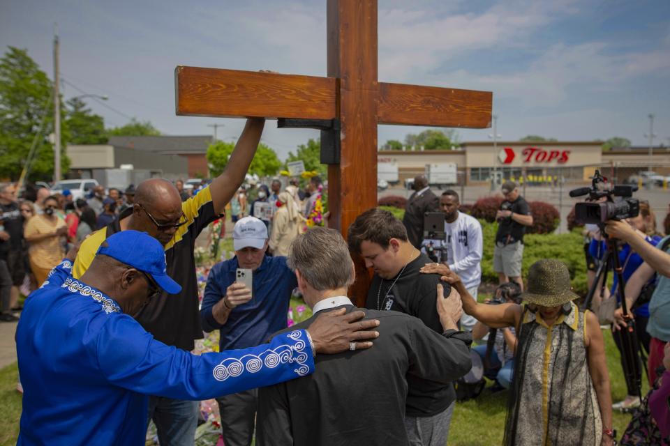 FILE - A group prays at the site of a memorial for the victims of the Buffalo supermarket shooting outside the Tops Friendly Market on Saturday, May 21, 2022, in Buffalo, N.Y. Funeral services are set for Friday for three of those killed: Geraldine Talley, Andre Mackniel and Margus Morrison. They are among the 10 people killed and three wounded May 14 when a white gunman opened fire on shoppers and employees at a Tops Friendly Market. (AP Photo/Joshua Bessex, File)