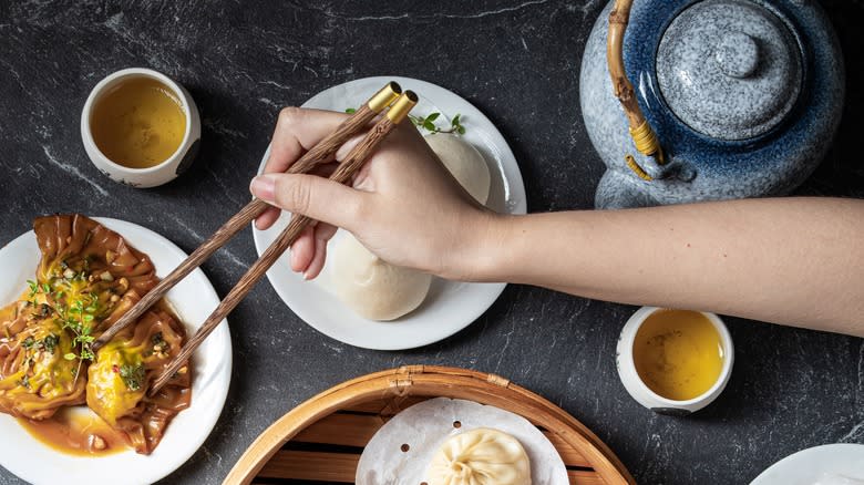 hand using chopsticks on dim sum