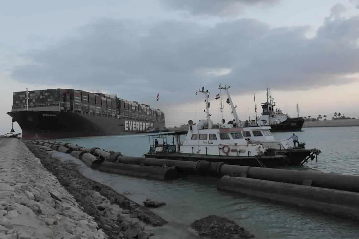 In this photo released by the Suez Canal Authority, tug boats work to free the Panama-flagged, Japanese-owned Ever Given, which is lodged across the Suez Canal, Sunday, March 28, 2021.