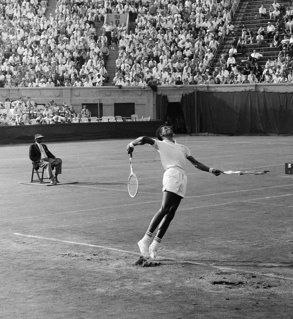 FILE - In this file photo of Sept. 10, 1965, Arthur Ashe, 22, serves during the National Tennis Championship at the West Side Tennis Club in the Forest Hills neighborhood of the Queens borough of New York. The stadium that was one of the cathedrals of tennis and hosted US Open tennis for six decades, as well as music greats, is planning to revive the sound of music at the 16,000-seat stadium and perhaps, one day, bring back big-time professional tennis. (AP Photo, File)