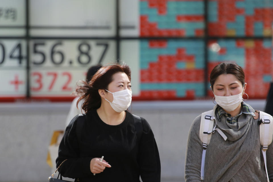 People wearing face masks walk by an electronic stock board of a securities firm in Tokyo, Tuesday, Feb. 16, 2021. Asian shares advanced on Tuesday, lifted by the economic recovery, vaccine rollouts and signs that new coronavirus cases may be abating. (AP Photo/Koji Sasahara)