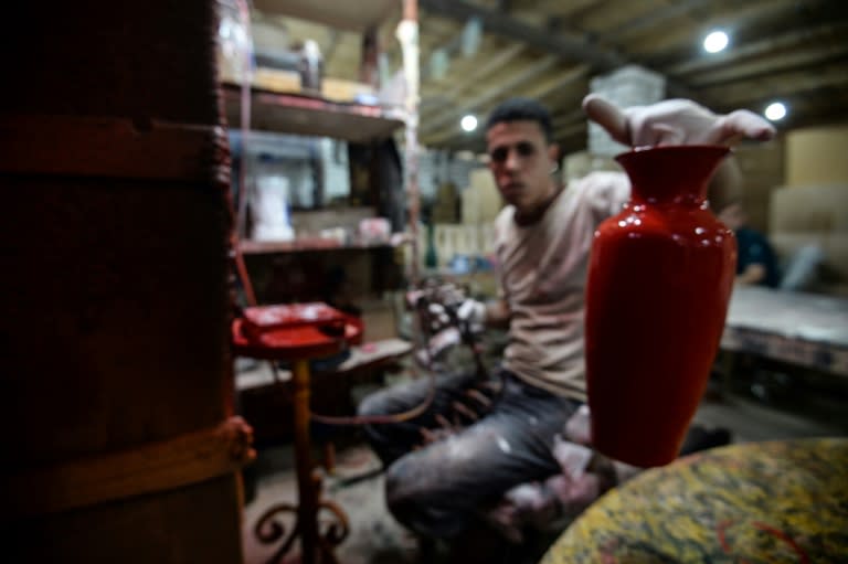 One of Mostafa el-Agoury's employees examines a vase at his pottery workshop on June 21, 2018