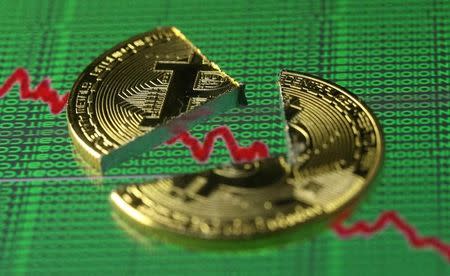 Broken representation of the Bitcoin virtual currency, placed on a monitor that displays stock graph and binary codes, are seen in this illustration picture, December 21, 2017. REUTERS/Dado Ruvic/Illustration/Files