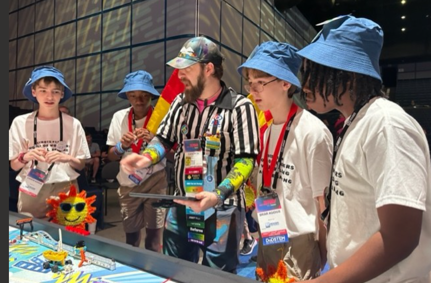 Four members of the Landmark Middle School robotics team -- from left, Carson Agidius, Kam'Ron Diamond, Briar Agidius and Kamaurie Sutherland -- interact with an event referee at the FIRST Lego League world championship in Houston.