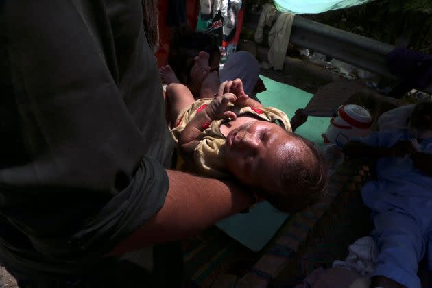 A mother carries her sick baby after floodwaters hit her home, in Charsadda, Pakistan on Aug. 31, 2022. (Photo: Muhammad Sajjad/AP)