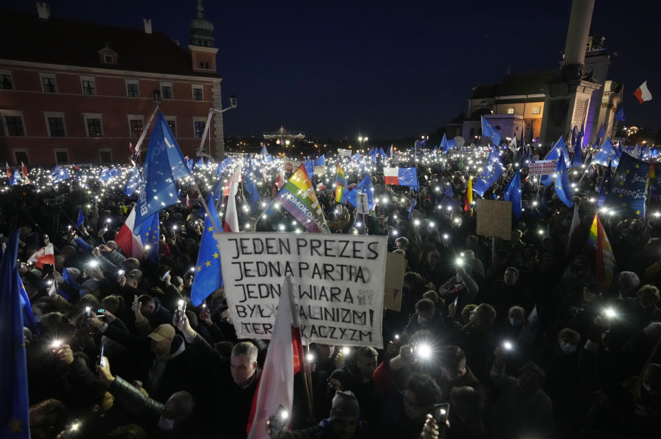 People hold up the flashlights of their mobile phones during a demonstration in support of Poland's EU membership in Warsaw, Poland, Sunday, October 10, 2021. Poland's constitutional court ruled Thursday that Polish laws have supremacy over those of the European Union in areas where they clash, a decision likely to embolden the country's right-wing government and worsen its already troubled relationship with the EU. Sign at center reads, "One leader, one party, one creed. Once it was Stalinism, now it's Kaczynski'ism." (AP Photo/Czarek Sokolowski)