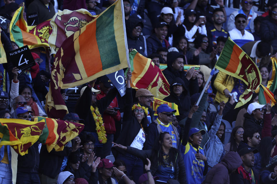 Cricket fans wave Sri Lankan flags during the T20 World Cup Cricket match between Sri Lanka and Namibia in Geelong, Australia, Sunday, Oct. 16, 2022. (AP Photo/Asanka Brendon Ratnayake)