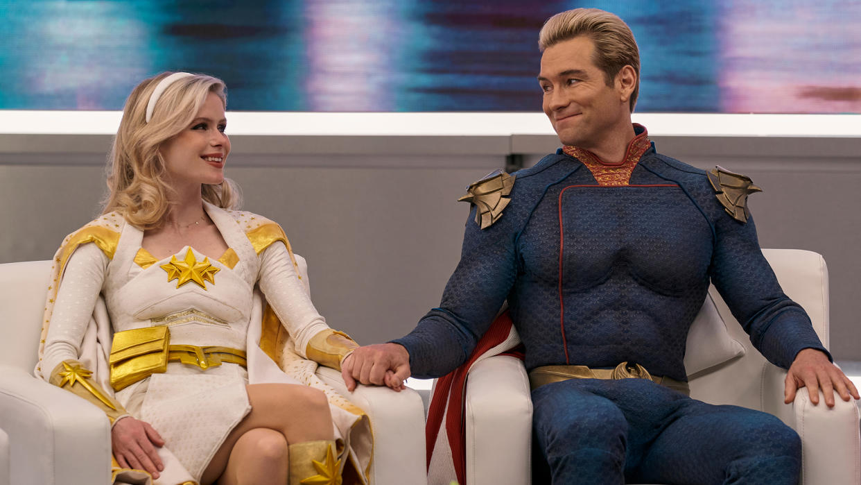  Erin Moriarty (Annie January aka Starlight) and Antony Starr (Homelander), holding hands as they look into each others eyes on a TV talk show in The Boys season 3 
