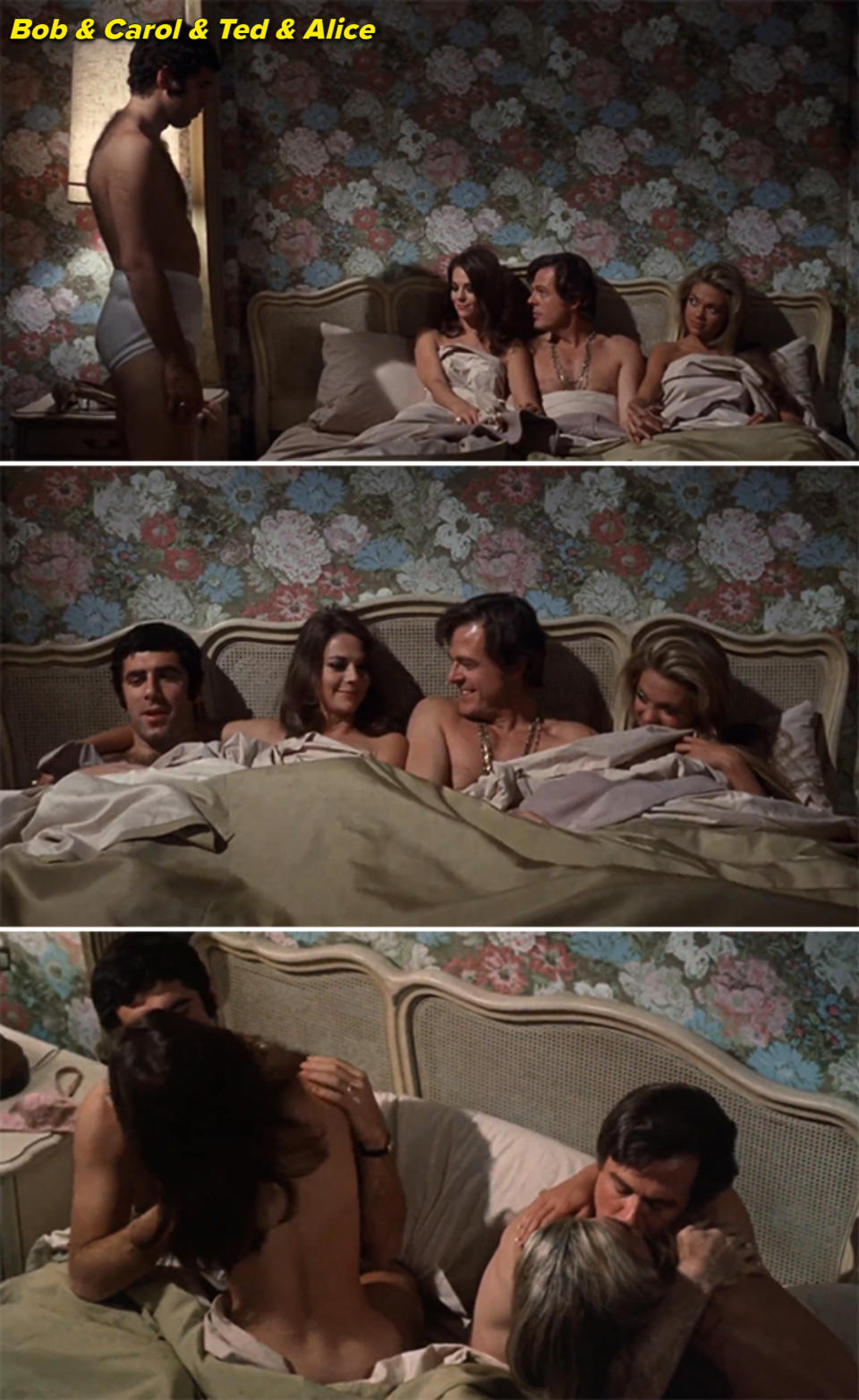 A man in underwear stands by a bed with a floral headboard. Four people are in bed, two women and two men, cuddling and conversing. Intimate scene