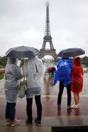 Tourists stroll on the Trocadero square, in front of the Eiffel Tower during a rainy day in Paris, France, May 30, 2016. REUTERS/Charles Platiau