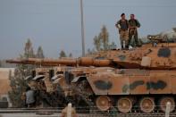 Turkish soldiers stand on top of a tank in the border town of Akcakale