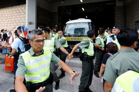 Officers from the Correctional Services Department escort a prison van leaving the High Court, in Hong Kong, China August 17, 2017. REUTERS/Tyrone Siu