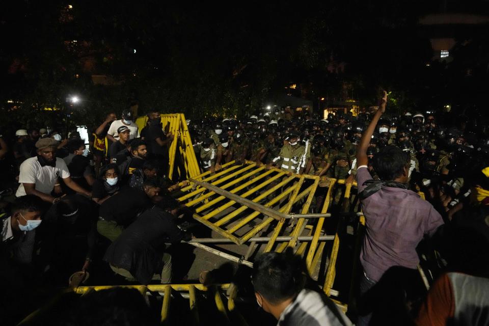 Protesters attempt to break a line of barricade as police and army soldiers block them near the president's official residence in Colombo, Sri Lanka, Saturday, May 28, 2022. Police fired tear gas and water canon on protesters who marched toward the president Gotabaya Rajapaksa's barricaded residence demanding his resignation. (AP Photo/Eranga Jayawardena)