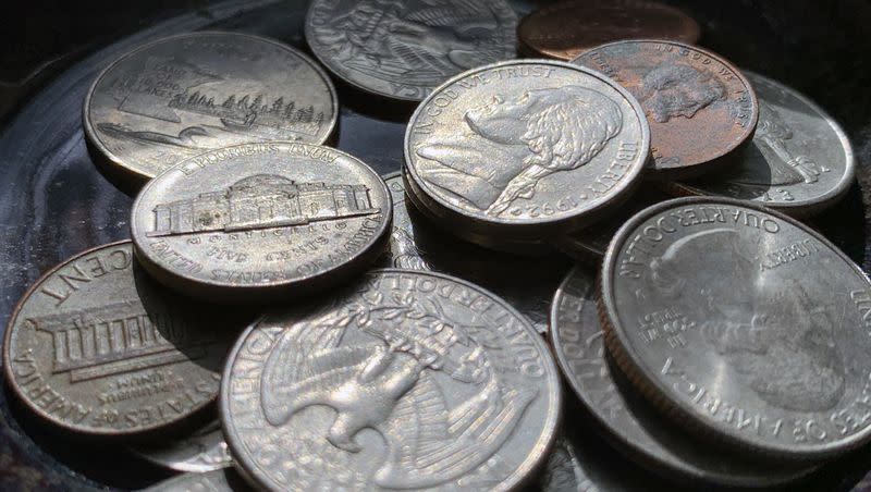 Quarters, nickels, dimes and pennies are held in a bowl Thursday, March 31, 2022, in Tigard, Ore.