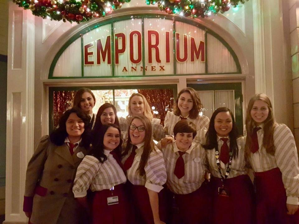 dana posing with her coworkers in front of the emporium at disney at christmastime