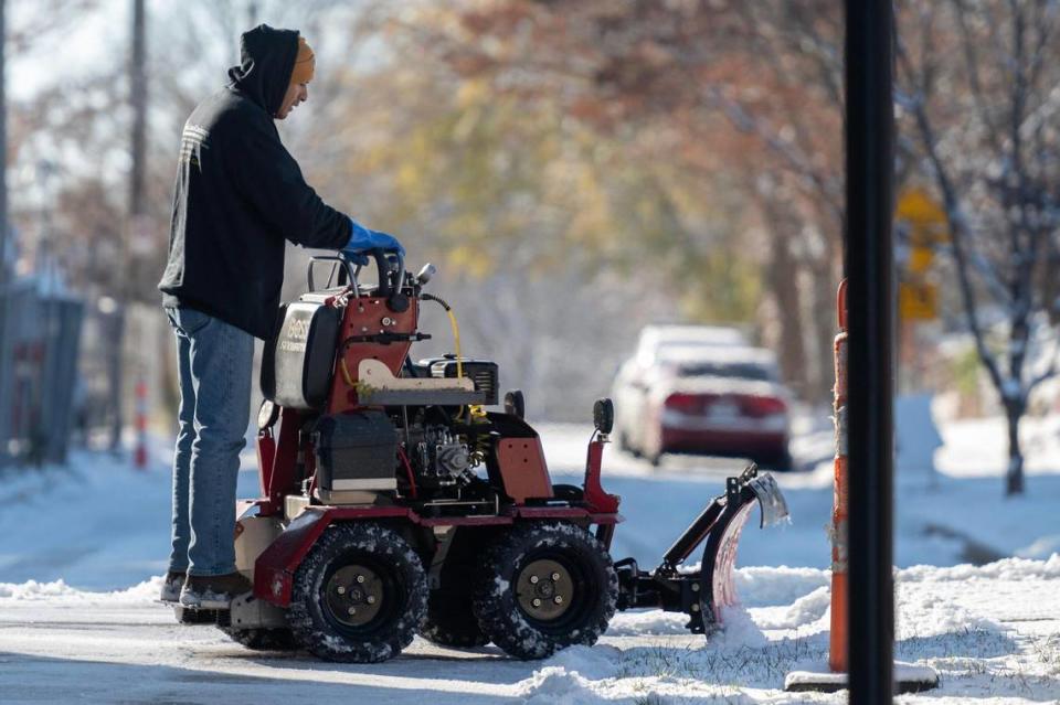 A groundskeeper plows snow off the sidewalk following Kansas City’s first snowfall of the season on Sunday, Nov. 26, 2023.