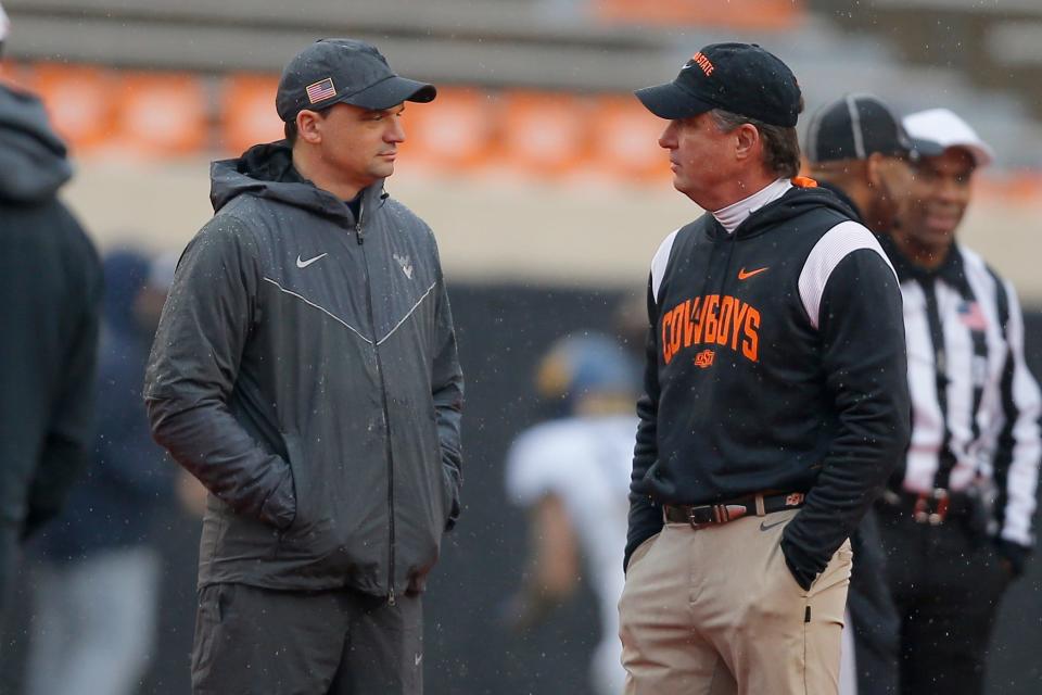 West Virginia Mountaineers head coach Neal Brown, left, and Oklahoma State Cowboys head coach Mike Gundy talk before a college football game between Oklahoma State and West Virginia at Boone Pickens Stadium in Stillwater, Okla., Saturday, Nov. 26, 2022.