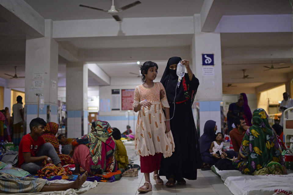 A child suffering from dengue is helped by a family member as she walks inside the dengue ward of Mugda Medical College and Hospital in Dhaka, Bangladesh, Thursday, Aug. 10, 2023. (AP Photo/Mahmud Hossain Opu)