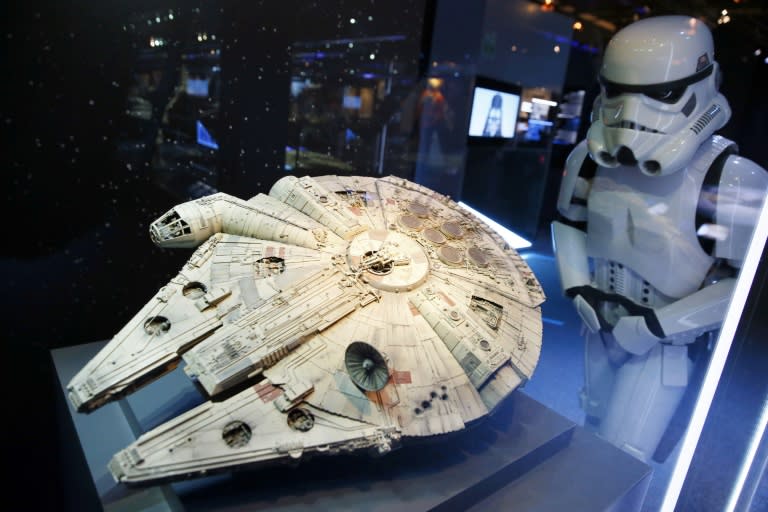 A performer dressed as a stormtrooper looks at a model of the Millenium Falcon starship from the Star Wars film series