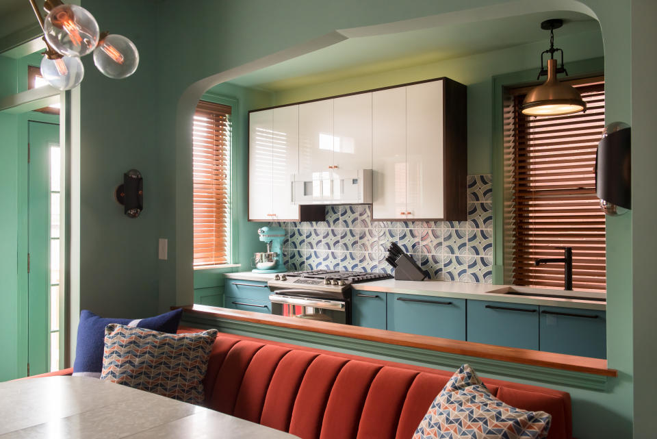 A kitchen painted green and a dining banquette in red