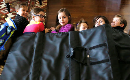 FILE PHOTO: Children demonstrate how they might take shelter in a school under a bulletproof blanket sold by Elite Sterling Security LLC (ESS) in Aurora, Colorado March 19, 2013. REUTERS/Rick Wilking/File Photo