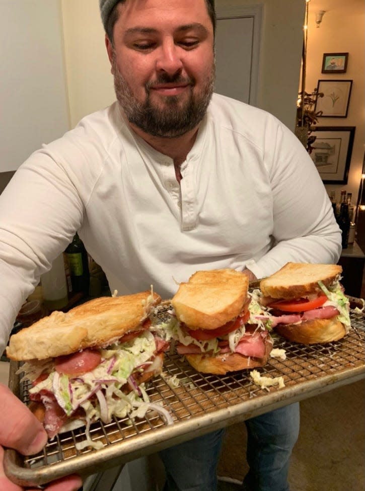 A picture of Wright holding a tray of Grinder Salad sandwiches.