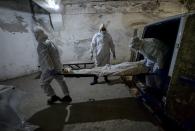 Pathologists in protective suits transport the body of a person who died of the coronavirus at a hospital's morgue in Bishkek, Kyrgyzstan, Wednesday, July 22, 2020. (AP Photo/Vladimir Voronin)