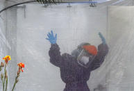 A health worker wearing a protective suit is disinfected inside a portable tent outside the Gat Andres Bonifacio Memorial Medical Center during an enhanced community quarantine to prevent the spread of the new coronavirus in Manila, Philippines, April 27, 2020. (AP Photo/Aaron Favila)