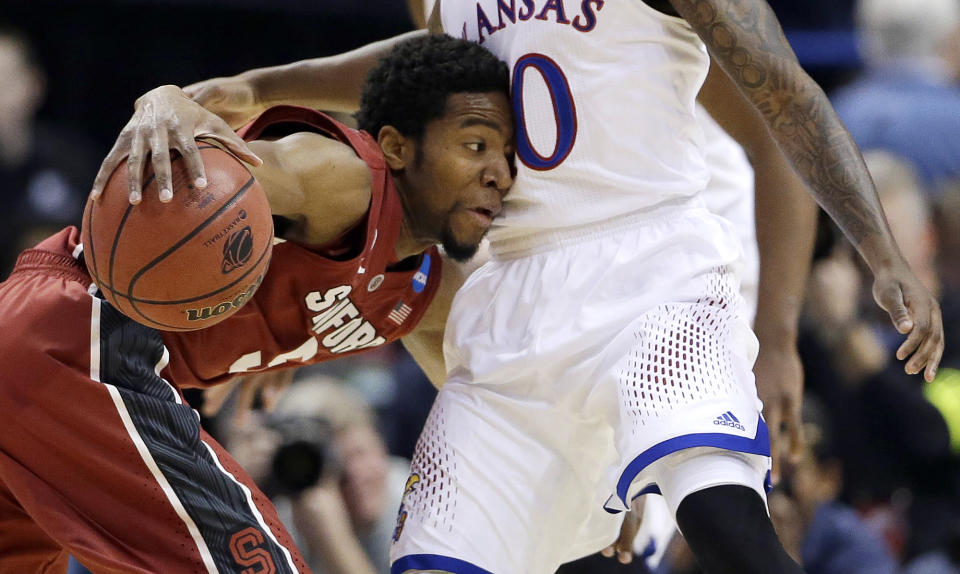 Stanford's Chasson Randle, left, tries to maneuver around Kansas' Naadir Tharpe, right, during the first half of a third-round game of the NCAA college basketball tournament Sunday, March 23, 2014, in St. Louis. (AP Photo/Jeff Roberson)